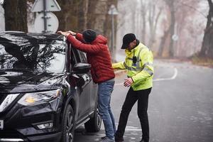 polis officer i grön enhetlig fångad bil stöld på de väg foto