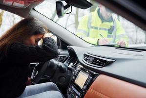 flickor känner dålig. manlig polis officer i grön enhetlig kontroll fordon på de väg foto
