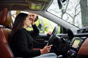 flickor känner dålig. manlig polis officer i grön enhetlig kontroll fordon på de väg foto