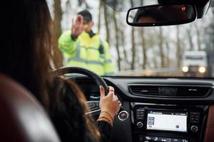 manlig polis officer i grön enhetlig stannar fordon med kvinna förare på de väg foto