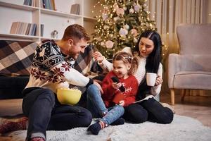 Lycklig familj inomhus i jul dekorerad rum fira ny år med popcorn foto