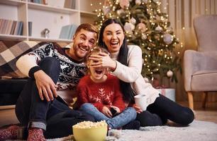 Lycklig familj inomhus i jul dekorerad rum fira ny år med popcorn foto
