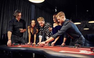 människor i elegant kläder stående och spelar poker i kasino tillsammans foto