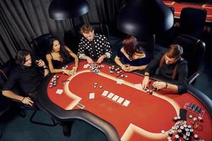 topp se av elegant ung människor den där spelar poker i kasino foto