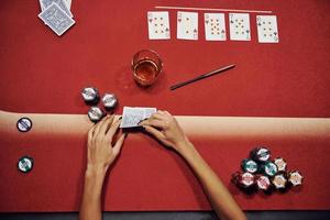 topp se av kvinnas händer. flicka spelar poker spel förbi tabell i kasino foto