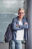 ung hipster kille i trevlig kläder står inomhus mot grå bakgrund foto