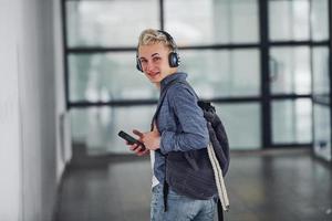 ung studerande i tillfällig kläder promenader inomhus med ryggsäck foto