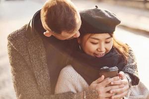 Lycklig raser par tillsammans utomhus i de stad. asiatisk flicka med henne caucasian pojkvän foto