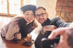 raser par framställning selfie i Kafé. asiatisk flicka med henne caucasian pojkvän foto