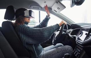 sida se av kvinna i virtuell verklighet glasögon den där Sammanträde inuti av modern bil foto