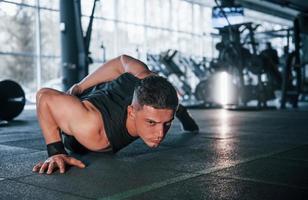 stark ung man i sportigt kläder håller på med skjuta på Posten i Gym foto