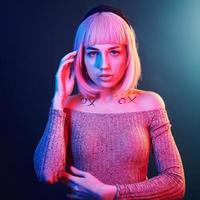 porträtt av ung flicka med blond hår i röd och blå neon i studio foto