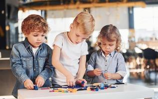 liten vänner ha roligt med konstruktion leksaker i lekrum. dagis pedagogisk spel foto