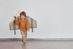 liten pojke i retro pilot enhetlig löpning med leksak plan inomhus foto