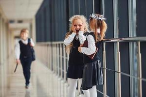 skola barn i enhetlig tillsammans i korridor. uppfattning av utbildning foto