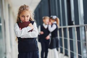 liten flicka får mobbad. uppfattning av trakasserier. skola barn i enhetlig tillsammans i korridor foto