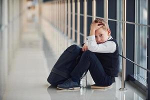 pojke i enhetlig Sammanträde ensam med känsla ledsen på skola. uppfattning av trakasserier foto