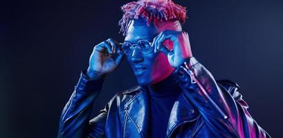 har roligt. trogen neon belysning. ung afrikansk amerikan man i de studio foto