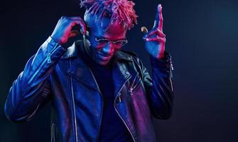 har roligt. trogen neon belysning. ung afrikansk amerikan man i de studio foto