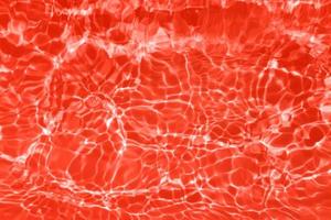 defokusering suddig transparent röd färgad klar lugna vatten yta textur med stänk och bubblor. trendig abstrakt natur bakgrund. vatten vågor i solljus med kopia Plats. röd vattenfärg lysande foto