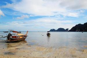 de se på de lång båtar på en kust av hav på en låg tidvatten. ö phi phi, thailand. foto