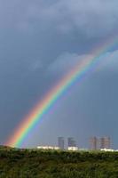 regnbåge i regn över stad och grön träd foto