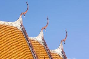 slutet av de gavel topp och de tak av de thai tempel kyrka - som är delikat och skön. de bakgrund av de blå himmel på en varm eftermiddag speglar de tak av de tak i en skön blänkande foto