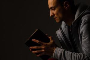 en man bön- innehav en helig bibeln. foto
