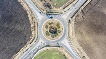 cirkel väg europeisk rondell korsning med liten trafik av bilar, cykel körfält och lantbruk fält runt om. vägar med rondell för bättre transport foto