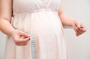 ung gravid kvinna mätning henne mage på Hem foto