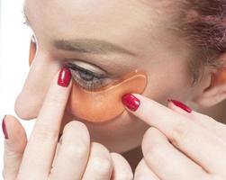 kvinna med kosmetisk plåster fuktgivande på hud under ögon. isolerat på vit bakgrund foto