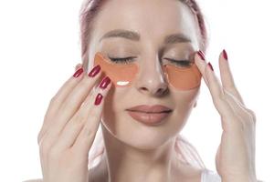 kvinna med kosmetisk plåster fuktgivande på hud under ögon. foto