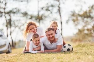 Lycklig familj utgifterna helgen tillsammans utomhus nära de skog. med dotter och son foto