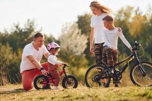 med Cyklar. Lycklig familj utgifterna helgen tillsammans utomhus nära de skog. med dotter och son foto