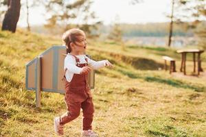 söt liten flicka med handgjorda vingar löpning utomhus på de fält och har roligt foto