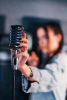 stänga upp se av mikrofon. ung skön kvinna artist övar i en inspelning studio foto