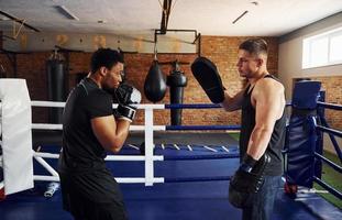 har boxning praktiskt. afrikansk amerikan man med vit kille ha träna dag i Gym foto