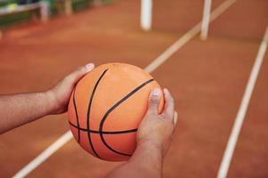 tredje person stänga upp se. afrikansk amerikan man spelar basketboll på de domstol utomhus foto