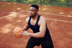 afrikansk amerikan man spelar basketboll på de domstol utomhus foto