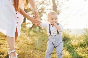 ung mor med henne liten son är utomhus i de skog. skön solsken foto