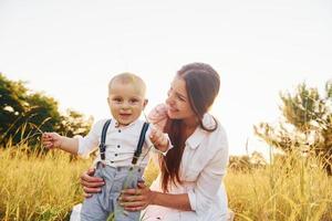 Lycklig familj leende och har roligt. ung mor med henne liten son är utomhus i de jordbruks fält. skön solsken foto