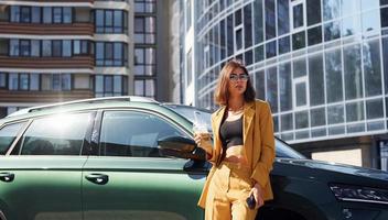ung modern kvinna i vinröd färgad täcka på dagtid med henne bil foto