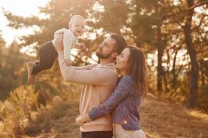 Lycklig familj av mor, familj och liten bebis vilar utomhus. skön solig höst natur foto