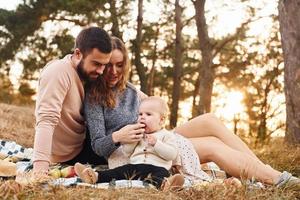 har picknick. Lycklig familj av mor, familj och liten bebis vilar utomhus. skön solig höst natur foto