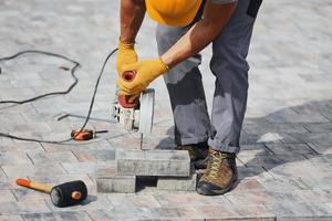 koncentrerad på arbete. man i gul färgad enhetlig ha jobb med trottoar foto