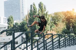 håller på med parkour. ung man i sportigt kläder ha träna utomhus på dagtid foto