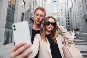 gör selfie. kvinna och man i de stad på dagtid. väl klädd människor foto