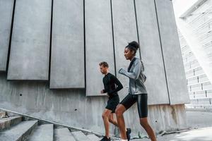 nära stor vägg. europeisk man och afrikansk amerikan kvinna i sportigt kläder ha träna tillsammans foto