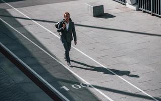 promenader på de väg. ung affärsman i grå formell ha på sig är utomhus i de stad foto