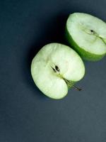 två halvor av en färsk grön äpple på en svart papper bakgrund foto
